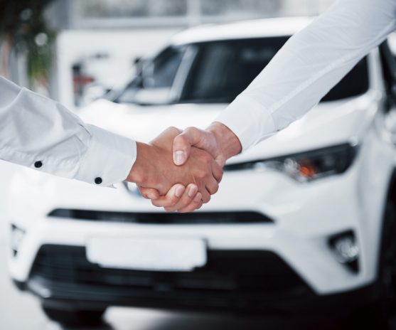 Close up of sales manager in black suit selling the car to the customer.